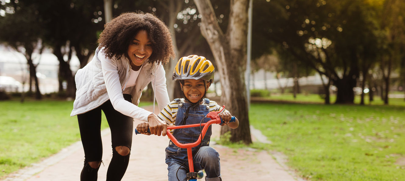 mother helping young son learn how to ride his bike