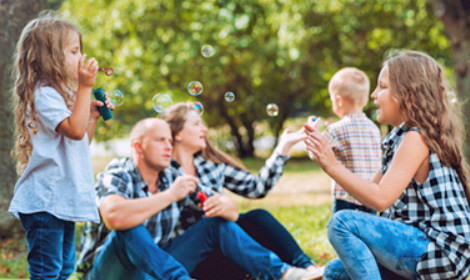 family of five blowing bubbles in an outdoor park