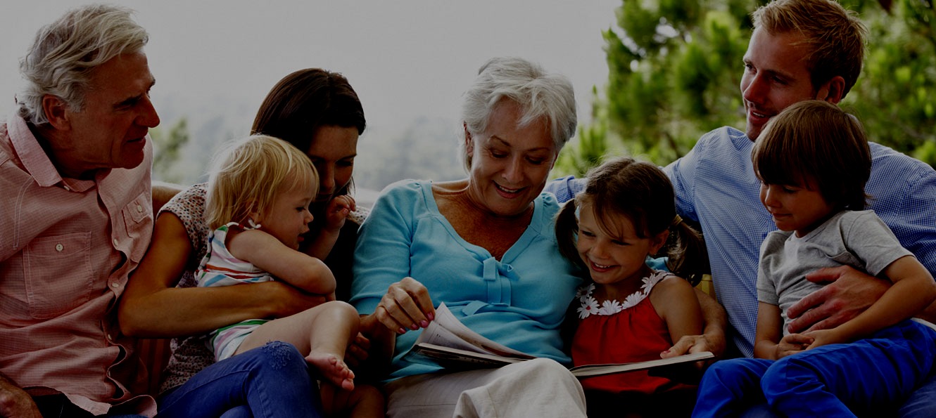 three generations of family sit together on a porch while reading a book