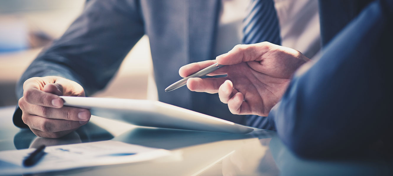 closeup of hands point to a tablet device during a business meeting