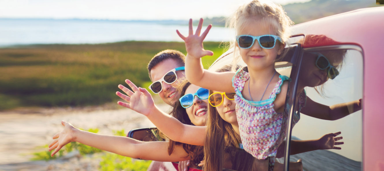 family of four wearing colorful sunglasses while hanging out of the car and waving