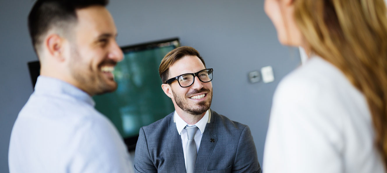 group of three business people in business attire talking in an office