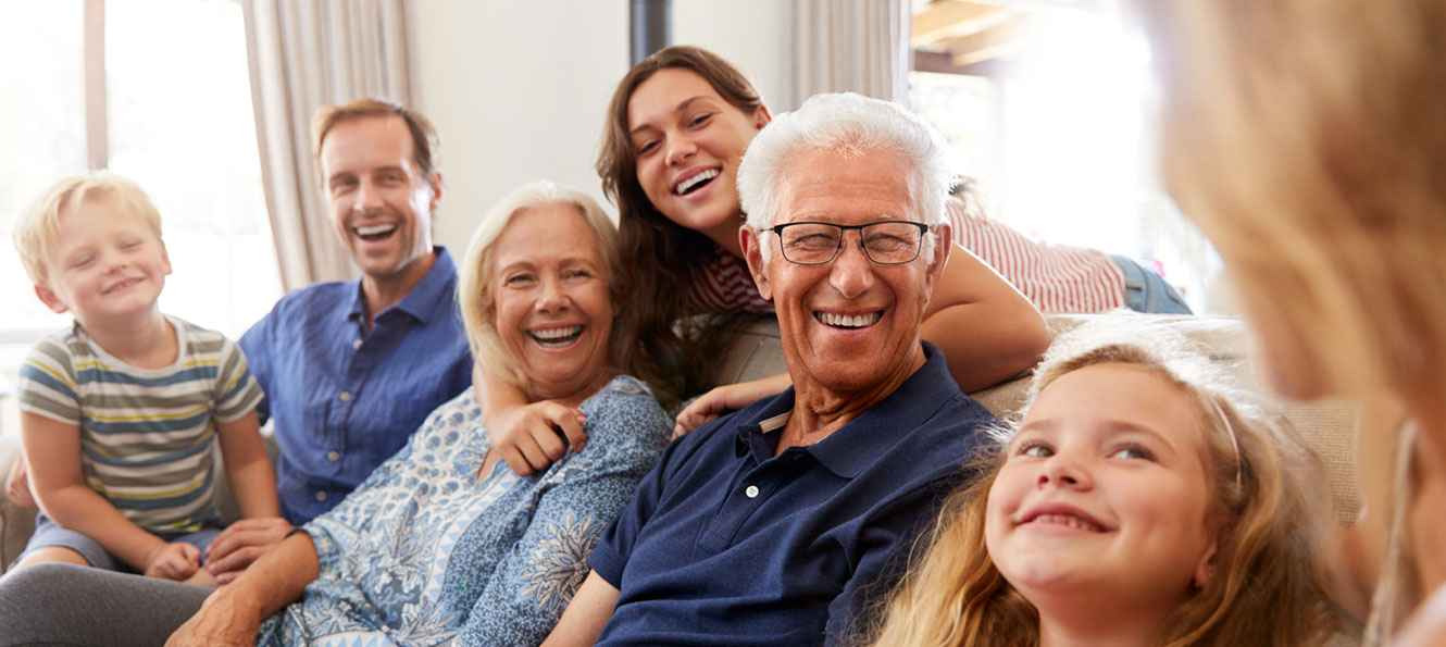 extended family sitting together in a living room and smiling at each other