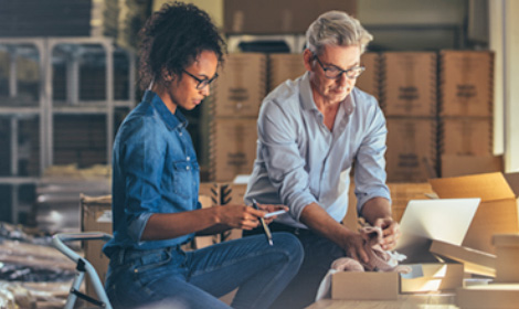 two employees in a small warehouse setting reviewing orders