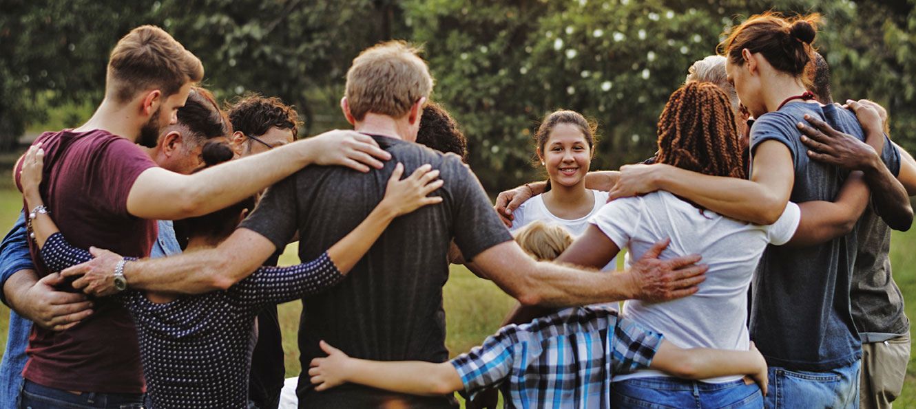 a group of people link together in a larger circle in an outdoor setting