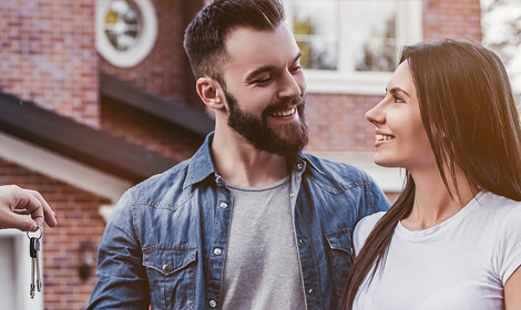 couple looking at each other while being handed home keys