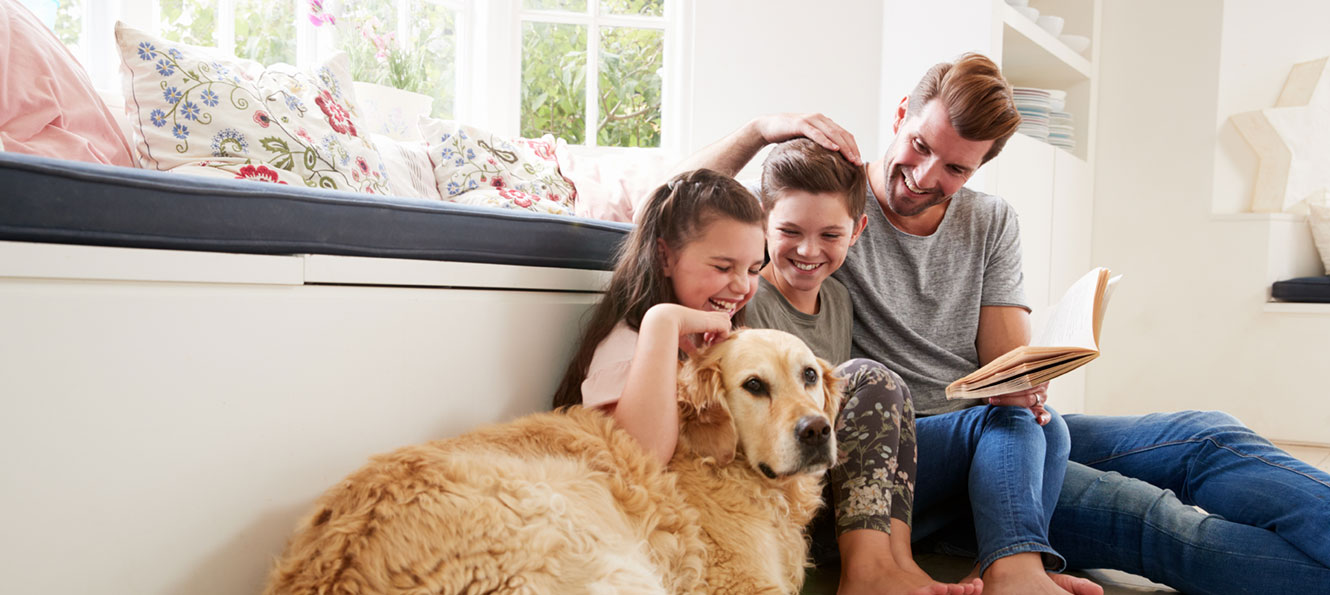 father reading to his children with the family dog nearby