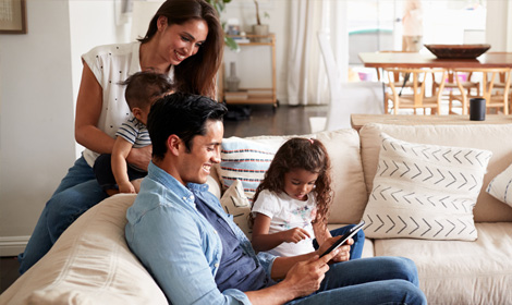 A family of four sits on the couch in their home enjoying some family time