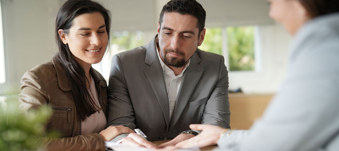 couple signing paperwork in an office