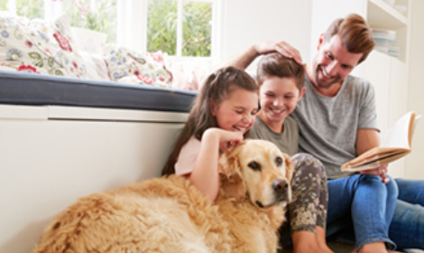 father reading to his children with the family dog nearby