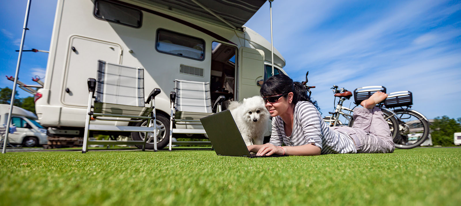 Woman lying on the grass with our her dog, enjoying the outdoors with her RV