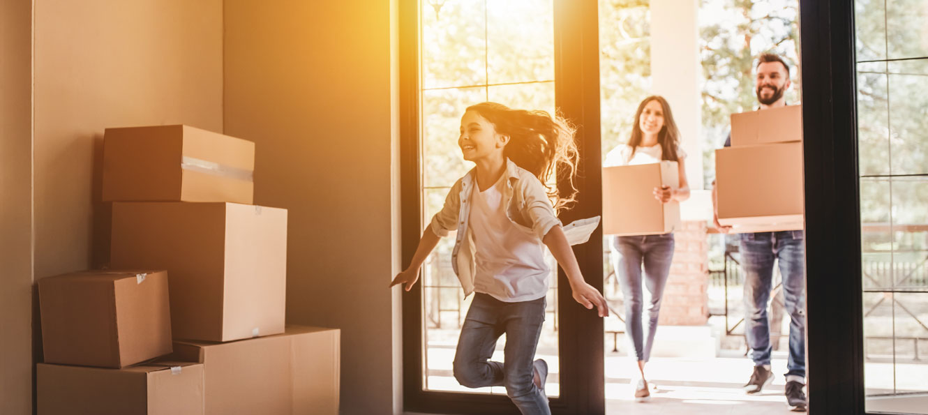 Family moving into a new home carrying boxes