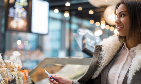 woman wearing a coat paying for food with her credit card