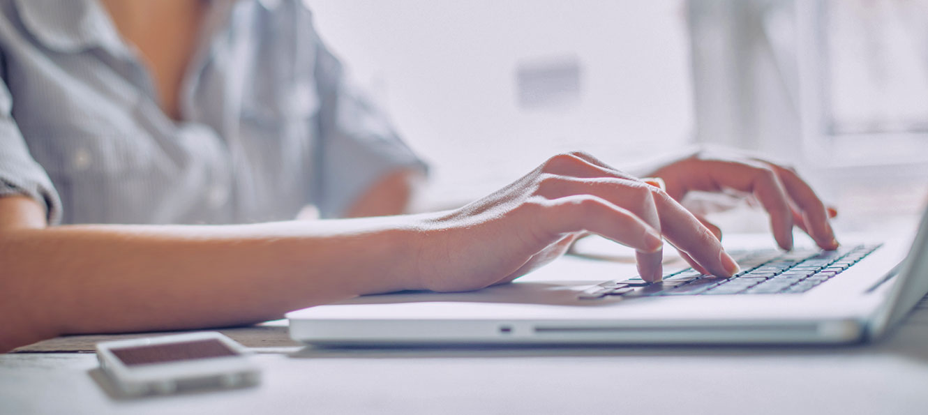 closeup of a woman's hands typing on a laptop keyboard