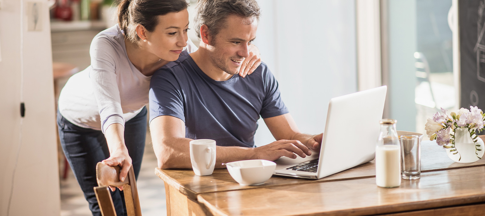 couple using a laptop on kitchen table