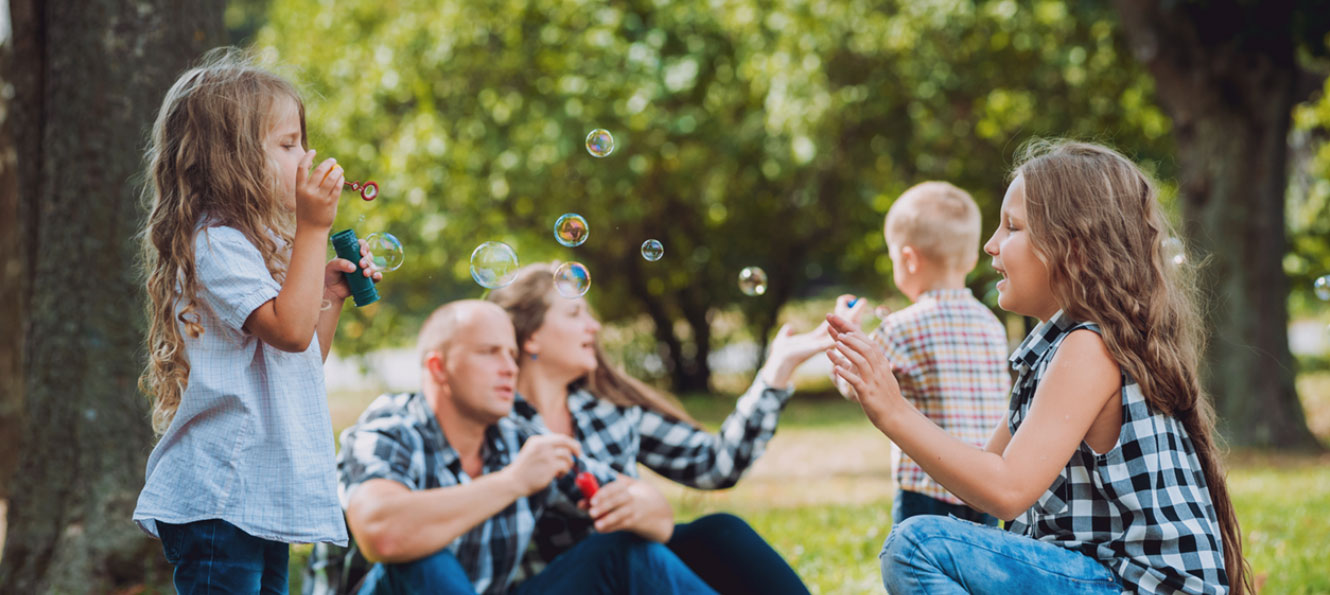 family of five blowing bubbles in an outdoor park