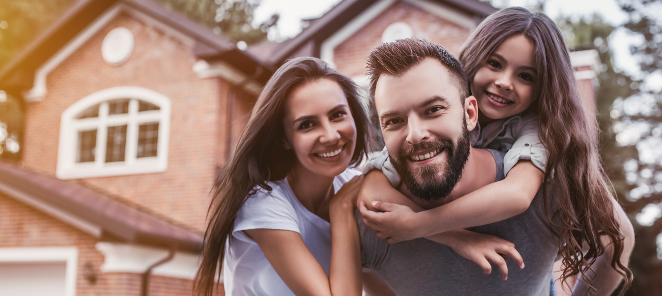 Smiling family of three outside of their home