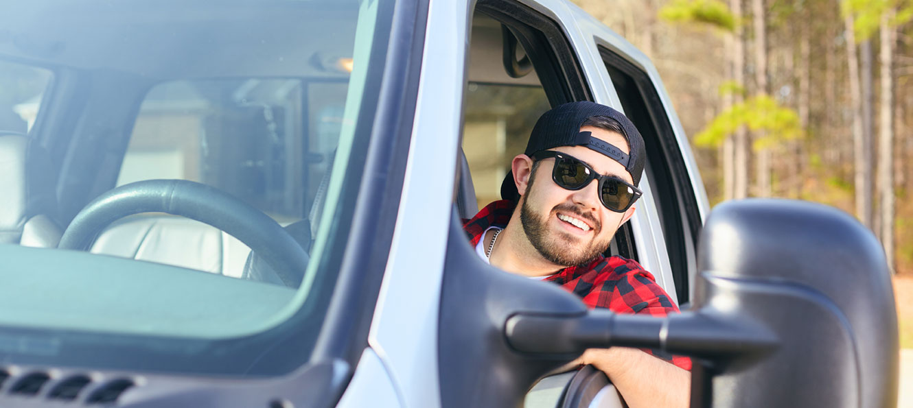 guy wearing sunglasses sitting in the drivers seat of his truck