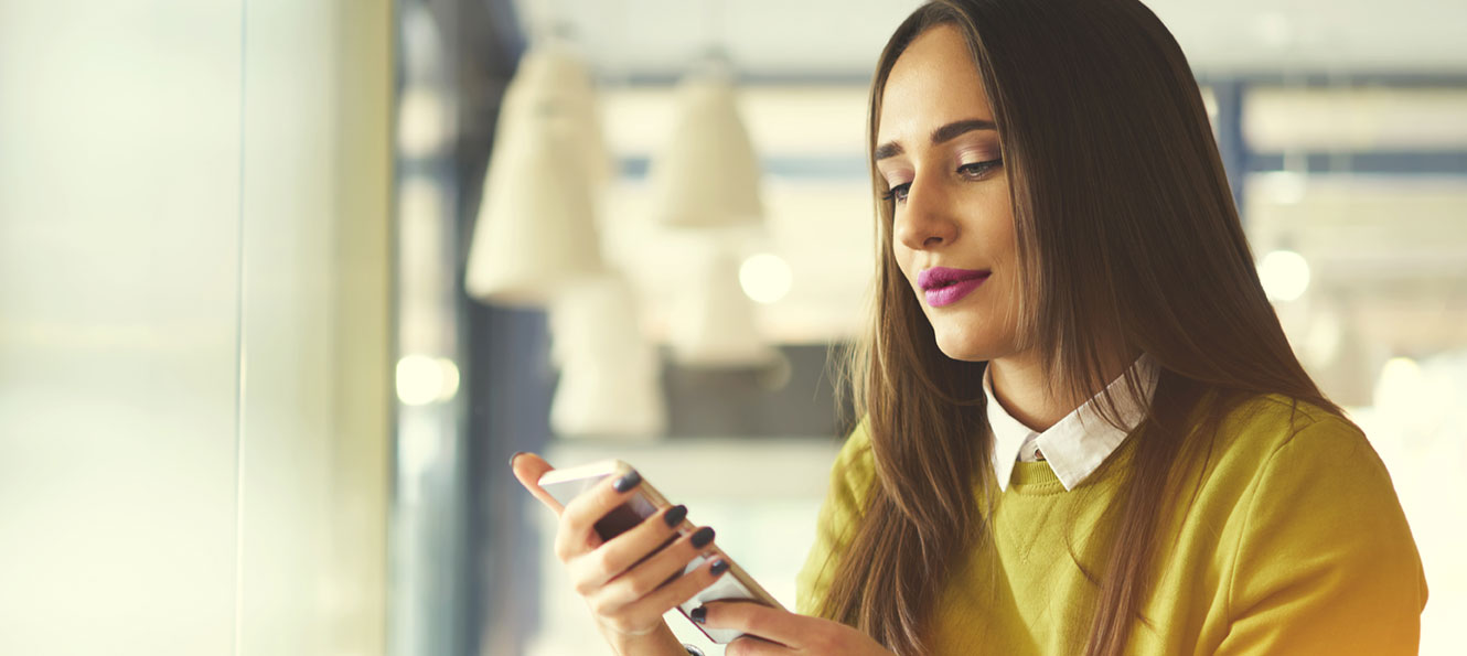 a young woman is sitting and looking at her smartphone