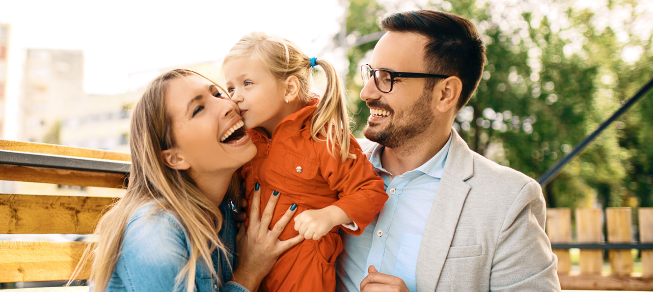 family of three smiling while enjoying the outdoors