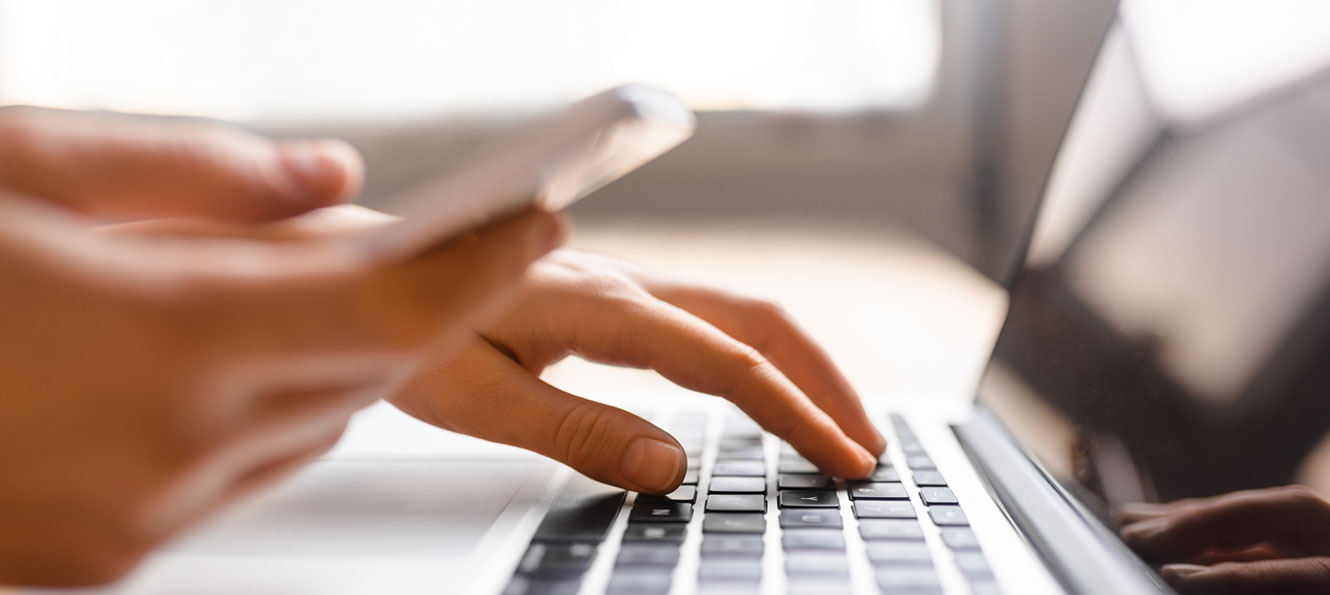 closeup of a person typing and holding a smartphone