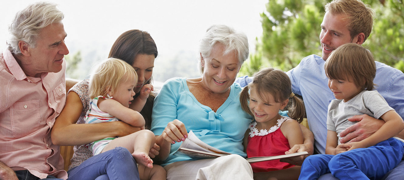 three generations of family sit together on a porch while reading a book