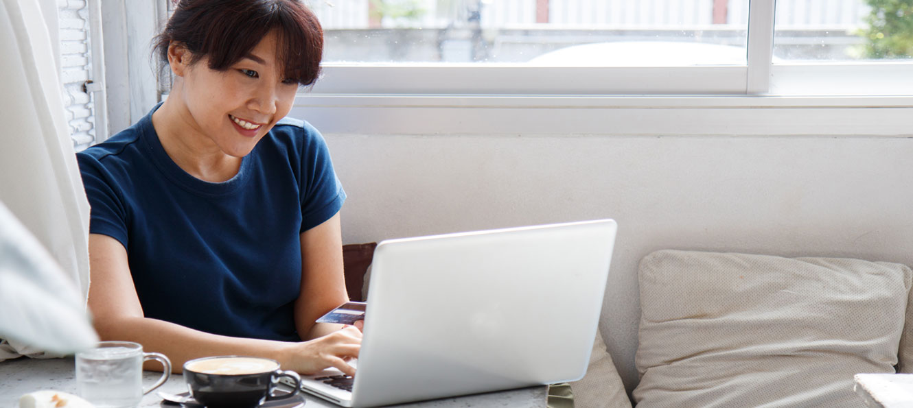 woman using her bank card in front of her laptop computer