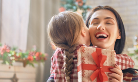 woman hugging a child while holding a gift in a holiday setting
