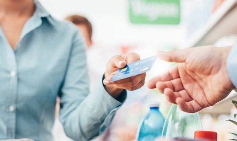 person handing over a credit card at payment inside a store