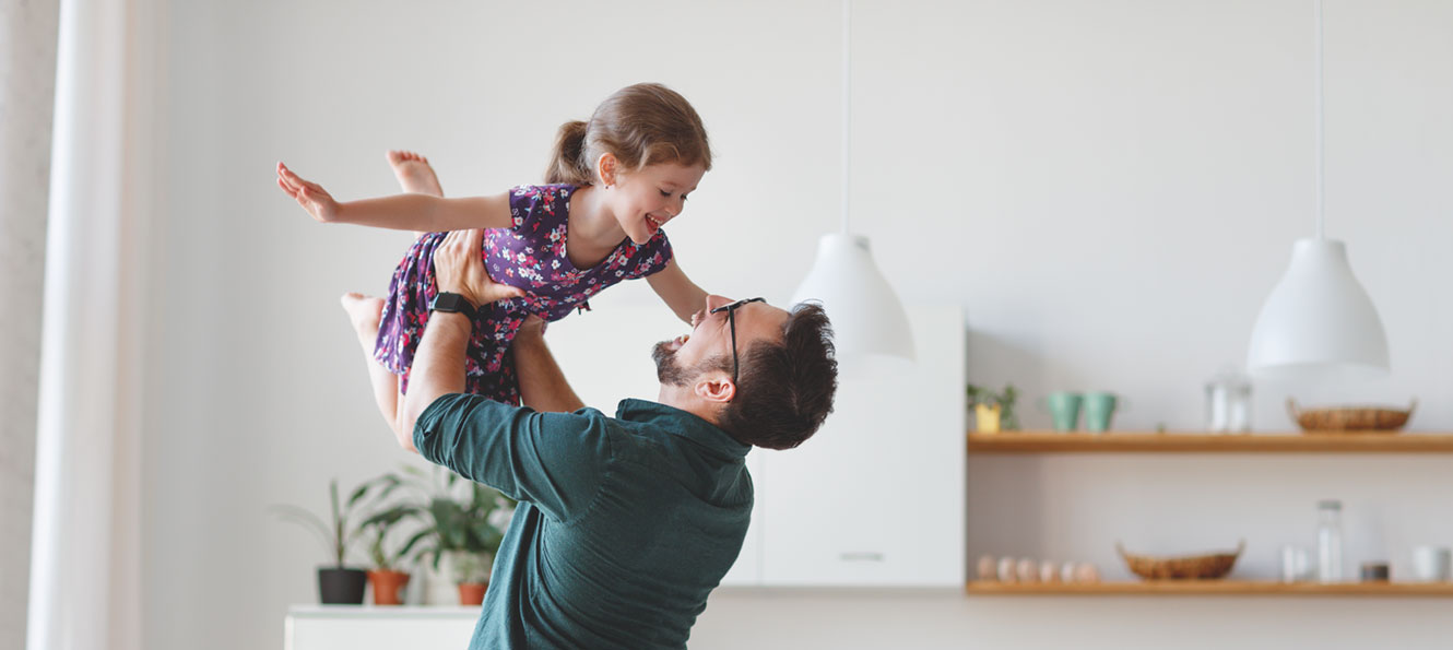 dad holding up his daughter while playing at home