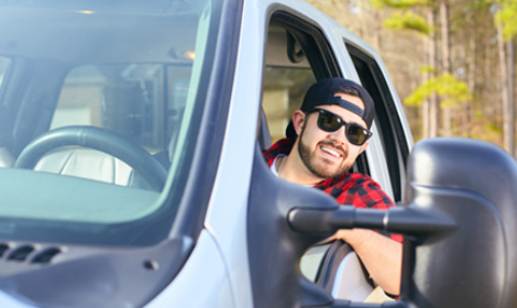 guy wearing sunglasses sitting in the drivers seat of his truck
